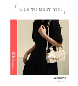 Detailed view of cream straw handbag with metal twist lock and yellow silk scarf handle