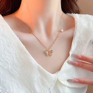 Detail of butterfly necklace with pink-green enamel, gold plating and pearl bead
