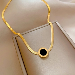 Detail of gold snake chain with a Roman numeral round black pendant on a jewelry box