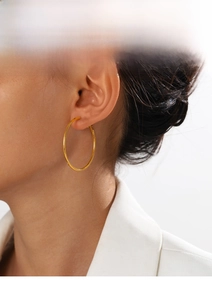 Close-up of large 18K gold plated stainless steel hoop earrings on model for a trendy look