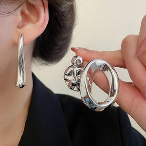 Macro detail of silver geometric earrings with a polished finish and abstract crinkled texture