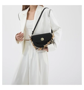 Detail of black saddle bag featuring gold twist lock and resin link chain strap