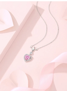 Detailed macro of pink heart pendant with crown design on silver chain over pink silk