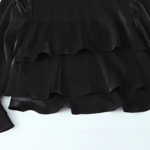 Women's black satin blouse with layered ruffle details and high-shine fabric finish