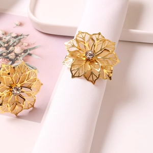 Golden flower napkin ring with mesh petals and rhinestone detail on white napkin