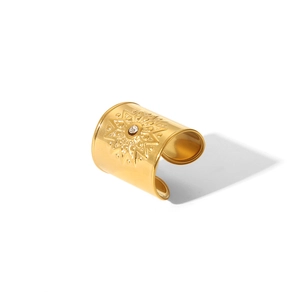 Close-up of golden sunburst textured open ring with a central sparkling crystal accent