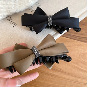 Detail of satin bow hair clips in black and green with sparkling rhinestone centers
