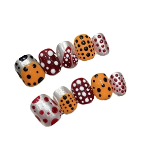 Faux ongles artistiques à pois aux couleurs vives variés sur fond blanc éclatant