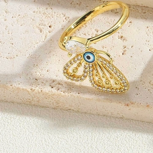 Detail of gold butterfly ring featuring evil eye charm and sparkling zircon stones