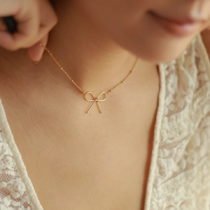 Elegant 18k gold plated stainless steel bow necklace shown on a model's collarbone