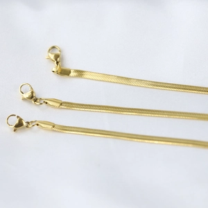 Detailed macro view showing three widths of gold snake chains with lobster clasps