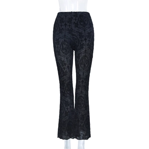Close-up of gothic lace patterns and cross motifs on black flare trousers fabric