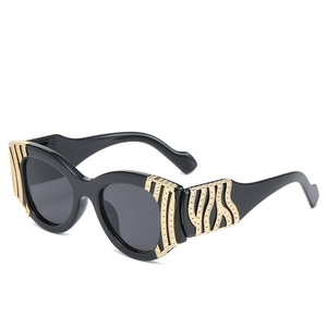 Vintage cat-eye sunglasses in black with gold wave-pattern metal accents on the temple