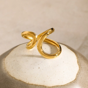 Detailed view of an 18K gold plated double wave open ring on elegant ceramic plate