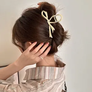 Elegant cream bow-shaped acrylic hair claw clip for women shown on styled hair