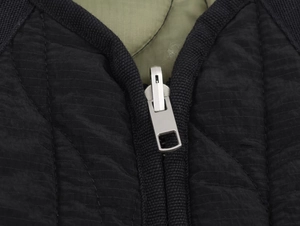 Detail of silver zipper with black quilted fabric and army green ripstop lining
