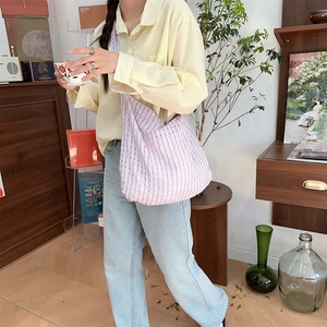 Détail d'un grand sac hobo à carreaux violets et blancs porté par un mannequin en intérieur