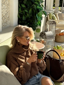Detailed texture of brown chunky knit turtleneck sweater in an outdoor setting