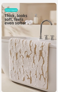 Detail of thick tufted bath mat with brown stripes hanging on a white bathtub edge
