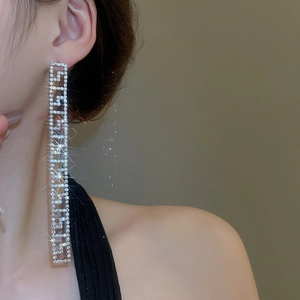 Macro di orecchini a nappa in argento con strass scintillanti indossati da una modella