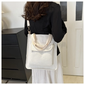 Macro shot of a white corduroy tote bag with front pocket carried on one shoulder