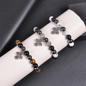 Détail de bracelets en œil de tigre de 10mm avec pendentifs croix sur présentoir