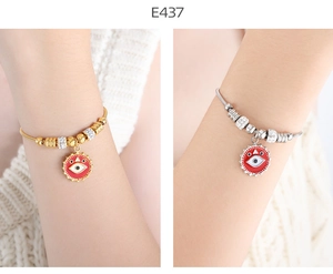 Detailed view of gold and silver evil eye charm bracelets with red enamel accents