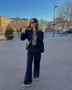 Scatto street style con giacca cropped blu scuro, pantaloni larghi e borsa a sella