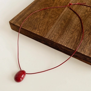Vue macro du pendentif ovale rouge vif sur un collier en cordelette rouge simple