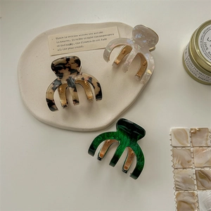 Three acetate hair claws in marble and tortoiseshell patterns on a white table
