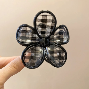 Detail of flower hair claw clip with black and white checkered pattern and glossy finish