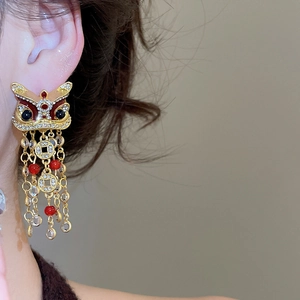 Vue détaillée d'une boucle d'oreille lion dansant doré avec pompons en pièces de monnaie
