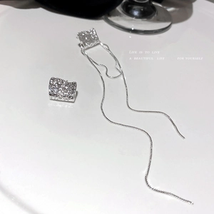 Boucles d'oreilles asymétriques argentées avec texture géométrique et pompons longs