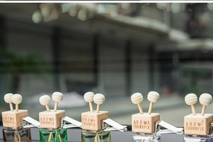 Row of colorful glass car perfume bottles with wooden caps and diffuser sticks
