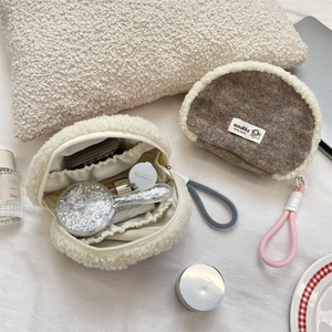 Detail of plush shell cosmetic bag with fuzzy trim, woven handle and interior storage