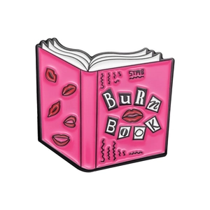 Macro view of pink Mean Girls Burn Book enamel pin with red lip prints and black edges