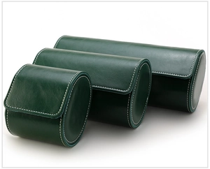 Three different sizes of green leather cylindrical watch cases with white stitching details