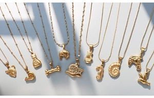 Detailed flat lay of diverse 18K gold-plated animal pendants and varied steel chains