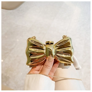 Close-up of a gold bow-shaped evening clutch with metallic finish and delicate chain