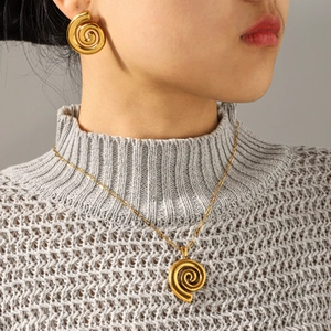 Close-up of polished 18k gold spiral necklace and earring set on a female model