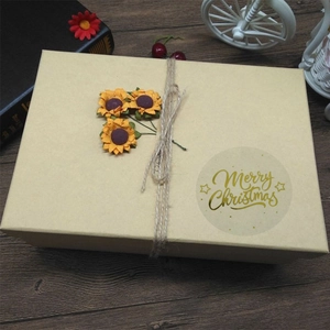 Transparent gold foil Merry Christmas stickers on a kraft paper gift box with twine