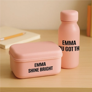 Pink lunch box and water bottle set on wooden desk with matte texture finish