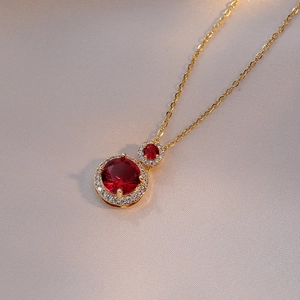 Golden necklace with double red faceted gemstone pendants and micro-pave zircon border