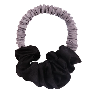 Detail of silk-texture hair scrunchie with grey pleated fabric and black bow design