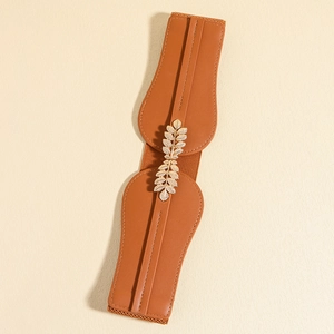 Detail of vintage elastic waist belt with brown leather and golden leaf metal buckle