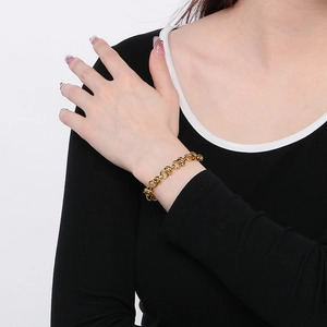 Vue détaillée d'un bracelet doré à maillons entrelacés porté par un mannequin au poignet