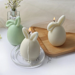 Detail of bunny easter egg candles in cream and green on a rustic wooden tray