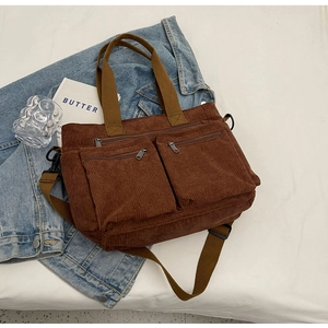 Brown corduroy handbag with front pockets, shown on white fabric with denim jacket
