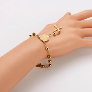 Golden rosary bead bracelet with Saint Benedict medal and cross on a hand model