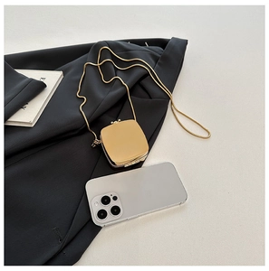 Close-up of elegant gold acrylic mini bag with chain strap on a professional backdrop